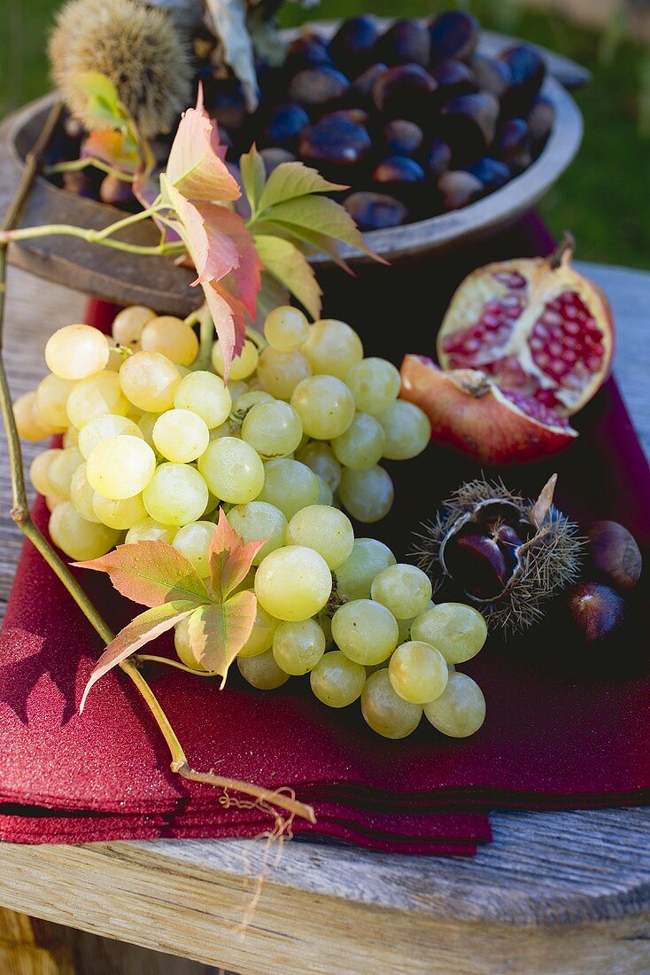 Trauben, Esskastanien, Granatapfel und Herbstlaub