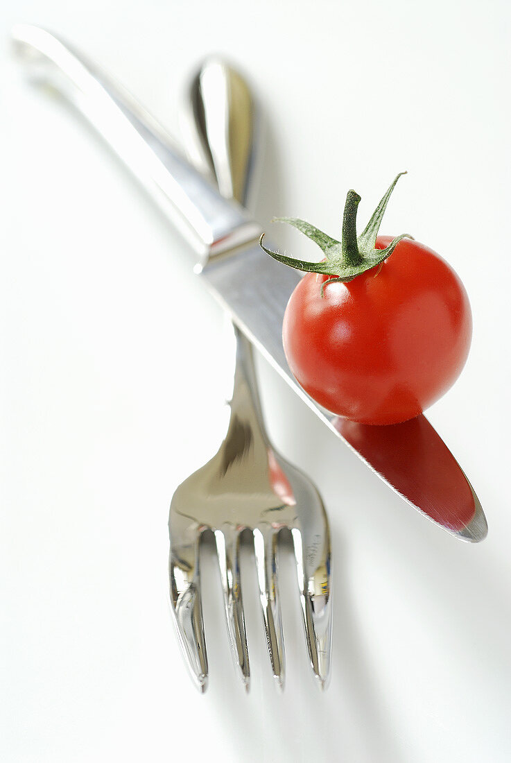Cherry tomato on knife over fork