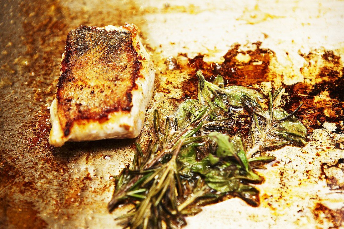 Roasted fish fillet with herbs on a baking tray