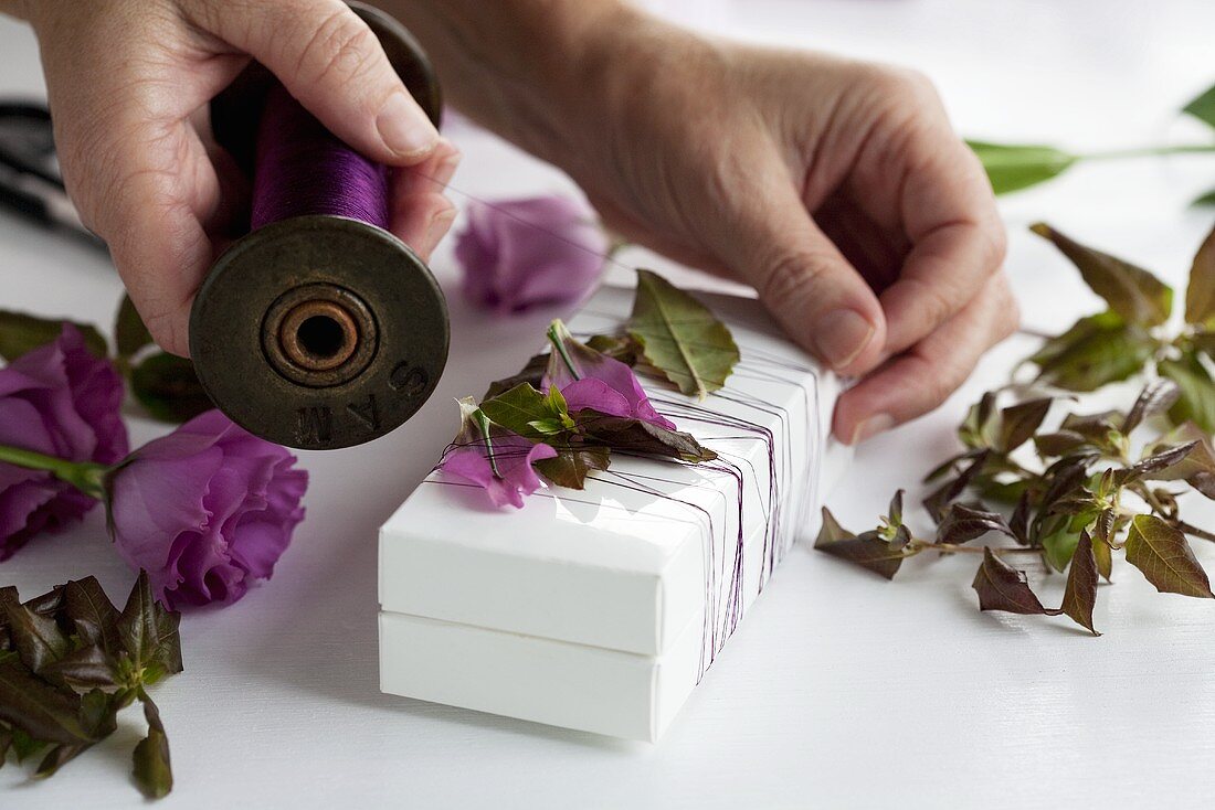 Decorating a gift box with lisianthus and twine