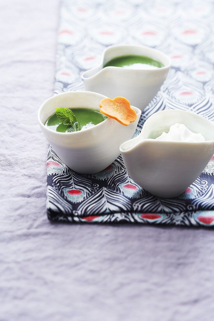 Two bowls of vegetable and lambs lettuce soup with whipped cream