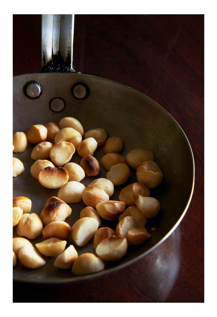 Macadamia nuts being roasted in a pan