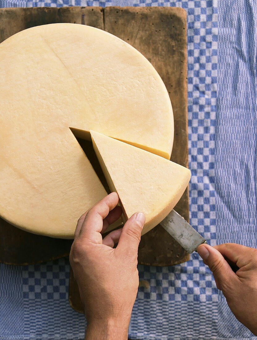 Cutting a slice of raclette cheese