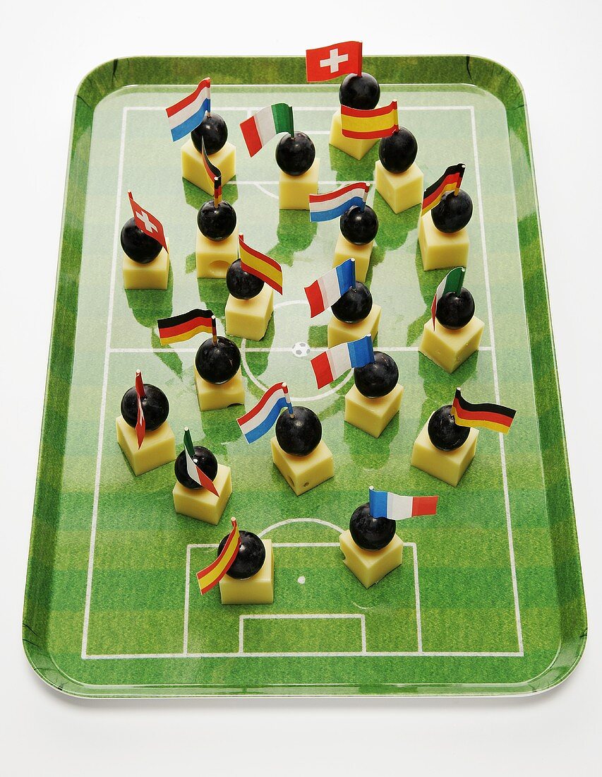 Cheese on cocktail sticks with flags on football pitch tray