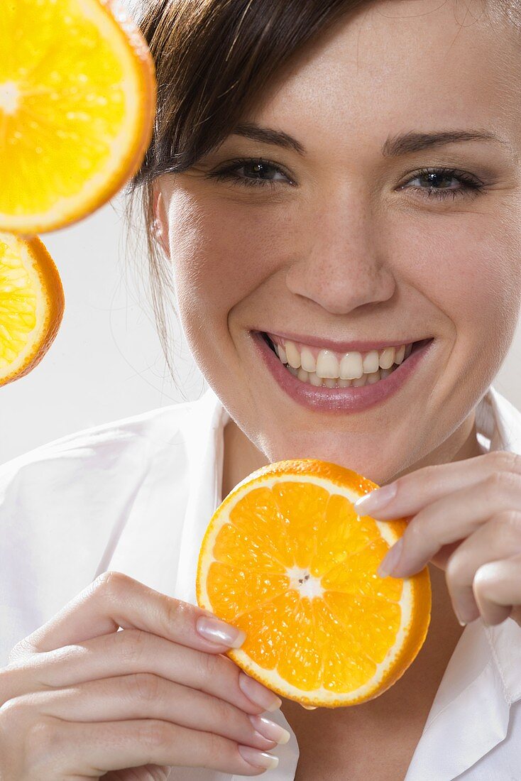 Junge Frau hält Orangenscheibe