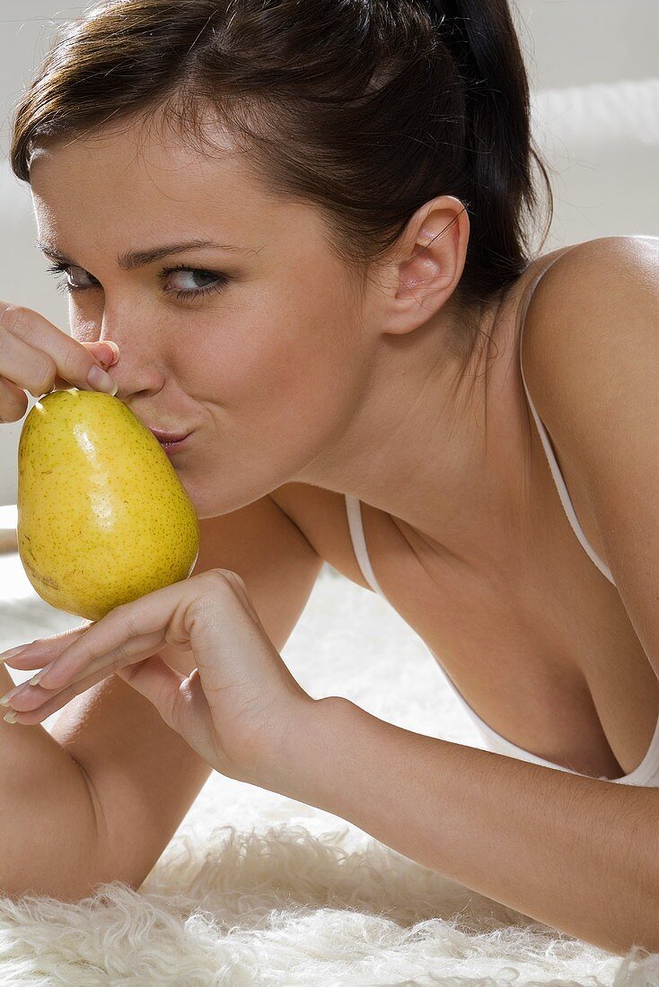 Junge Frau küsst eine Birne auf dem Bett