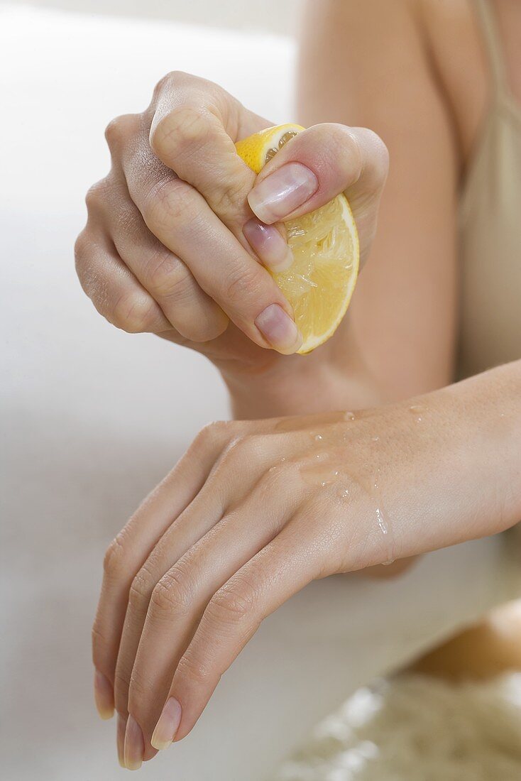 Woman squeezing lemon juice onto her hand