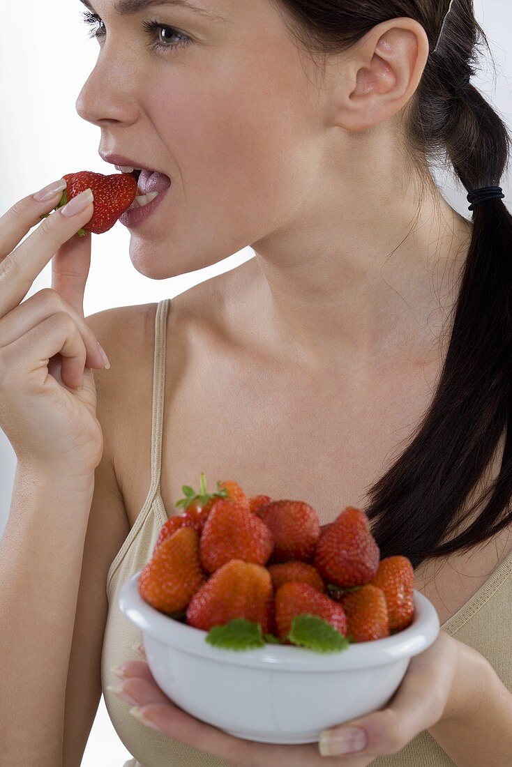 Junge Frau isst frische Erdbeere
