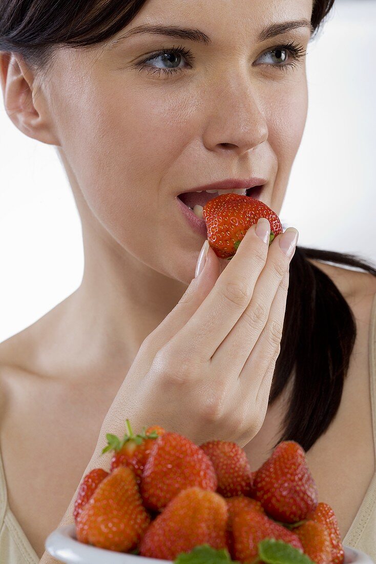 Young woman eating fresh strawberry