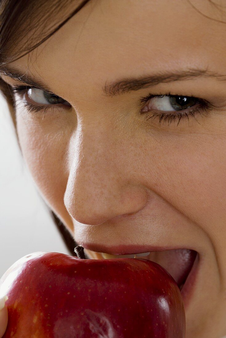 Junge Frau beisst in einen roten Apfel