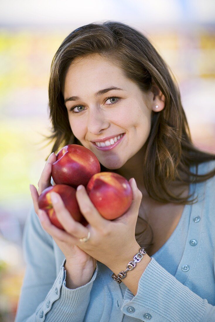 Young woman holding nectarines in her hand