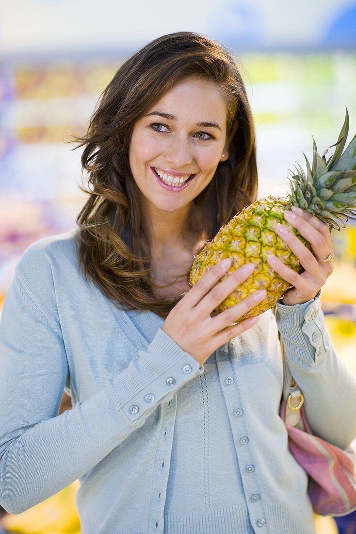 Junge Frau mit Ananas in einem Supermarkt