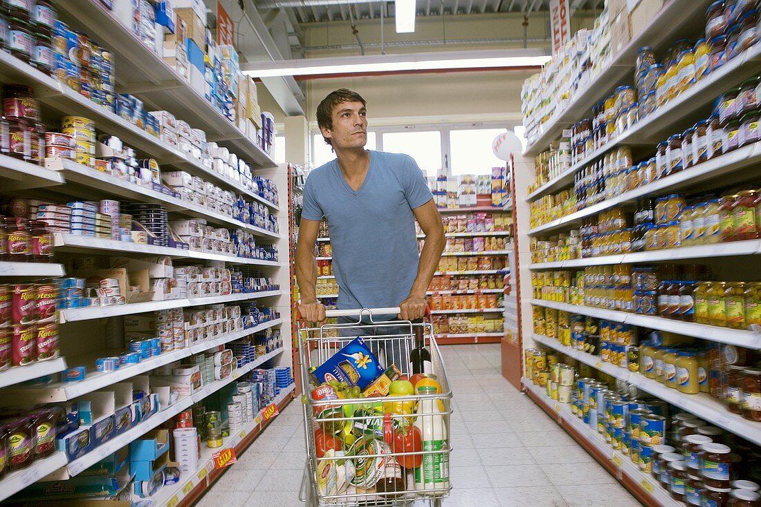 Junger Mann mit Einkaufswagen in einem Supermarkt