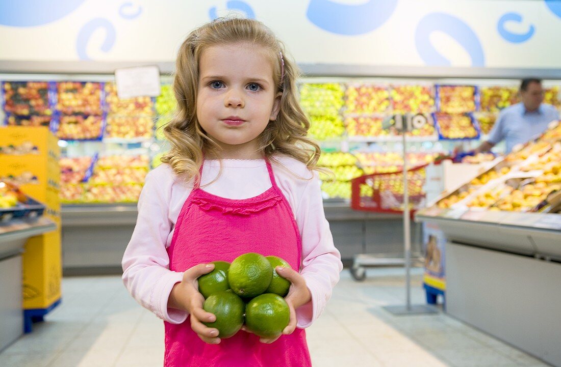 Girl holding limes in her hand in a supermarket