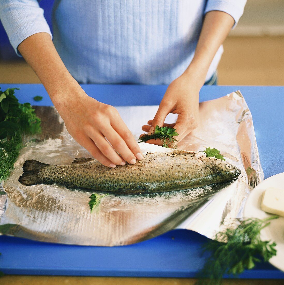 Preparing trout with herbs in foil