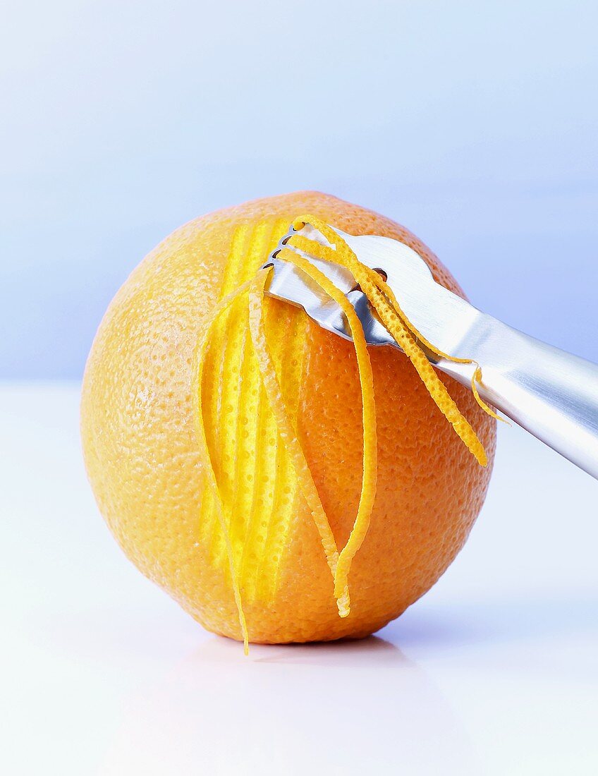 Orangenzesten mit einem Zestenreisser schneiden