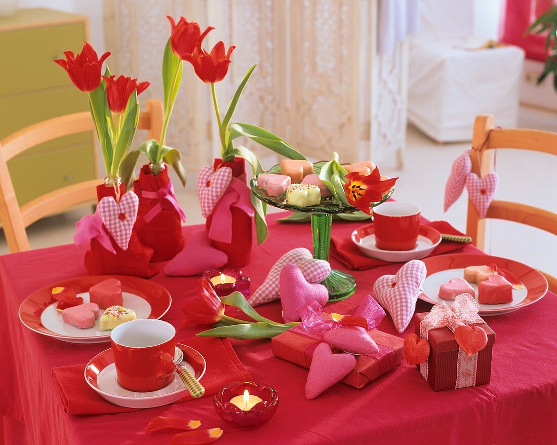 Red table decoration with tulips, fabric hearts and gifts
