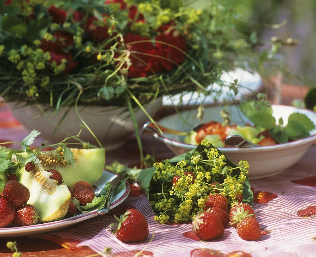 Sommertisch mit Erdbeeren und Honigmelone und Frauenmantel