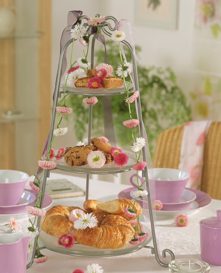Small cakes, croissants and daisies on tiered stand