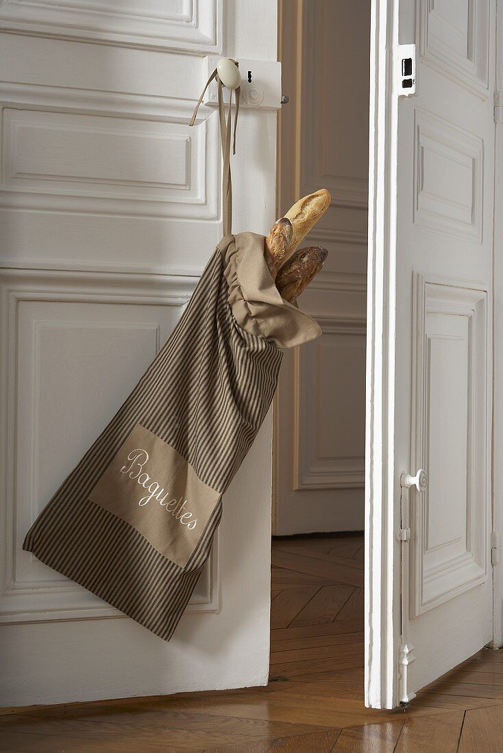 Baguettes in fabric bag on an apartment door