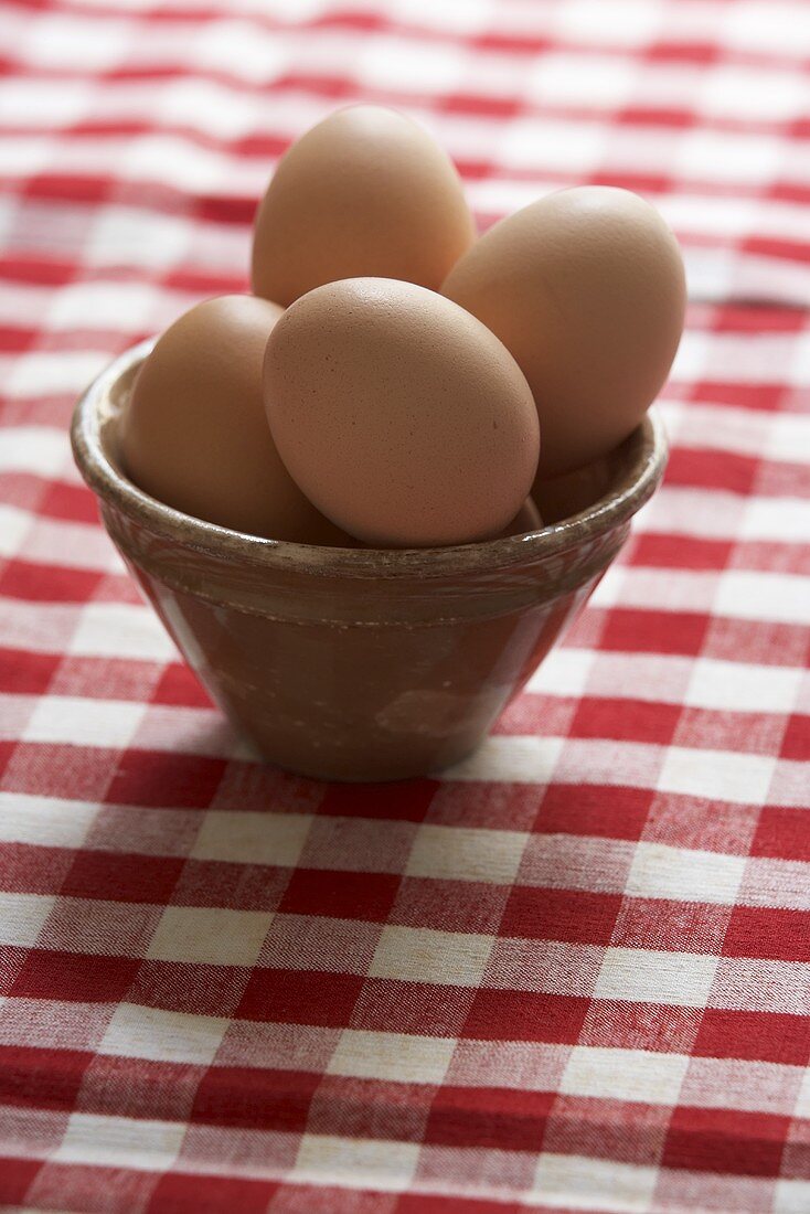 Eggs in brown basin on checked tablecloth