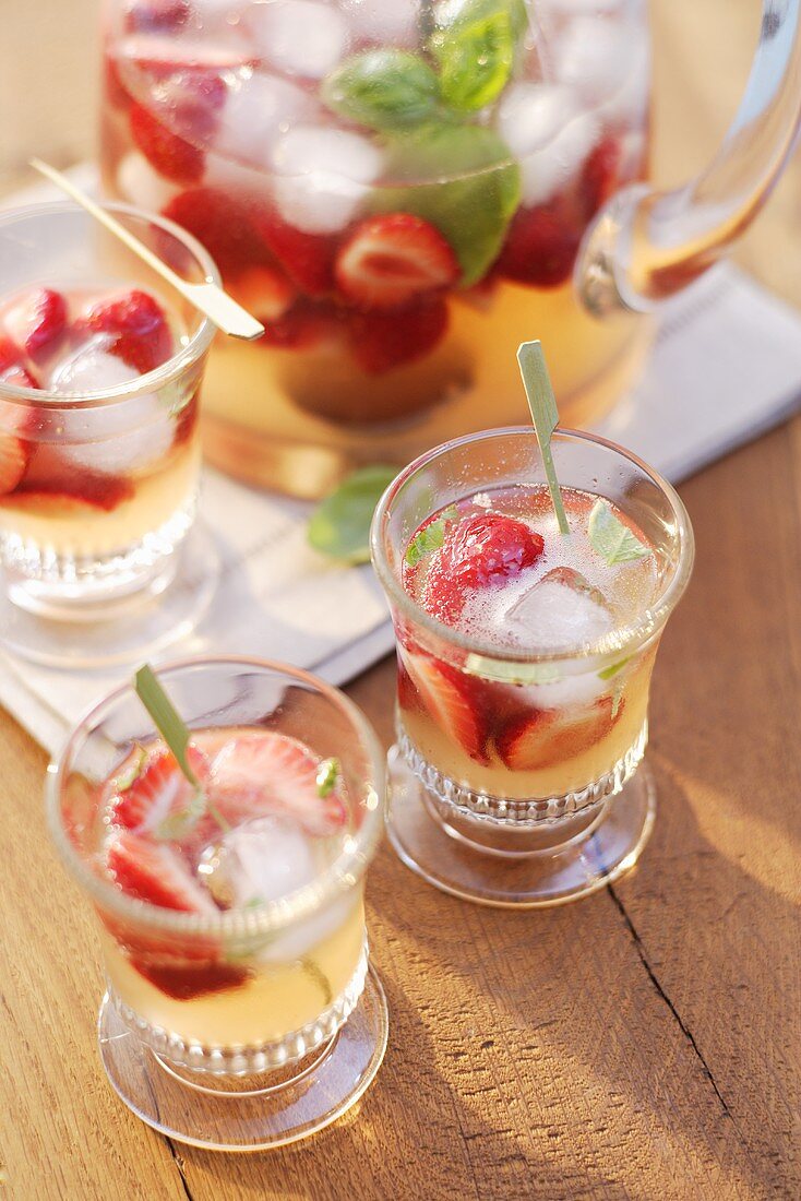 Erdbeerbowle mit Basilikum in Gläsern und Glaskrug