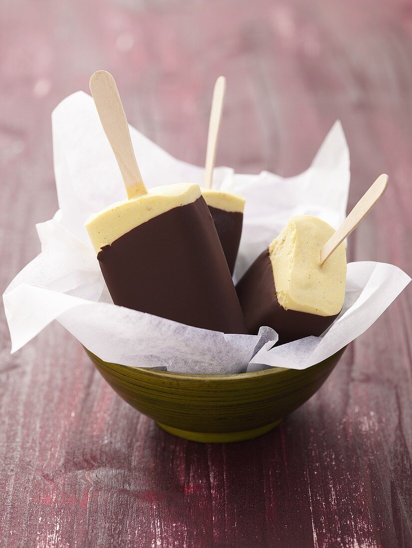 Chocolate-coated banana ice cream lollies in bowl