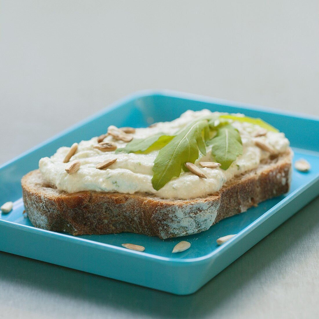 Brot mit Käsecreme, Sonnenblumenkernen und Rucola