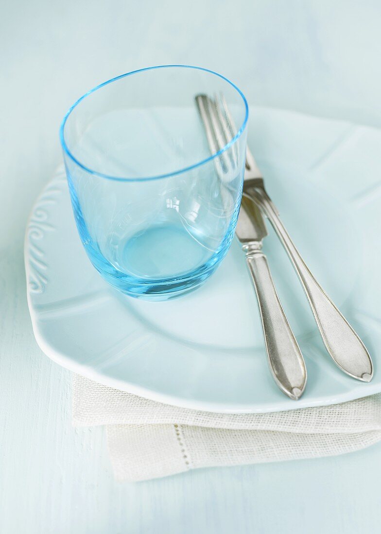 Empty glass and cutlery on white plate