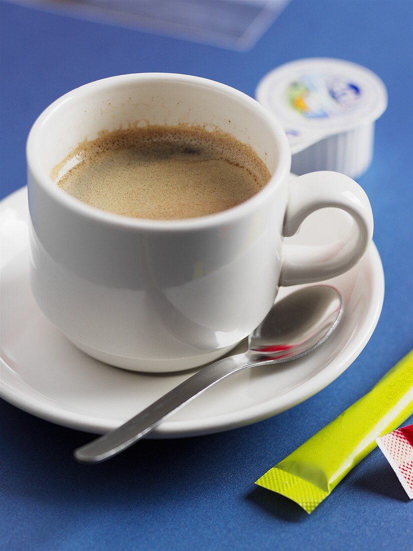 Tasse Espresso, Zuckertütchen und Sahne