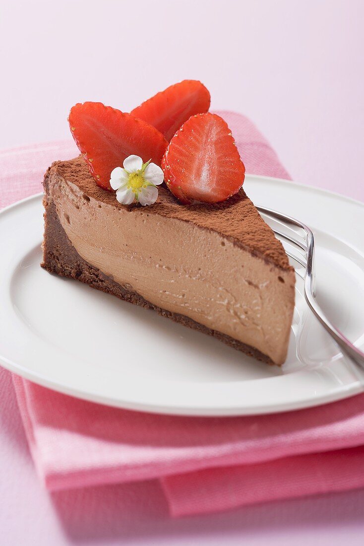 Piece of chocolate cheesecake with strawberries & cocoa powder