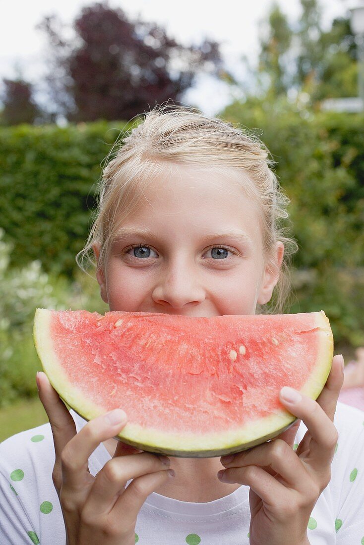 Girl holding a slice of watermelon out of doors