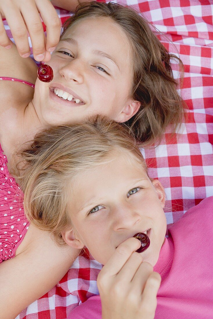 Zwei Mädchen mit Kirschen auf Picknickdecke