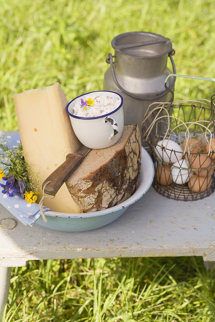 Rustikales Stillleben mit Brot, Käse, Eiern und Milchkanne