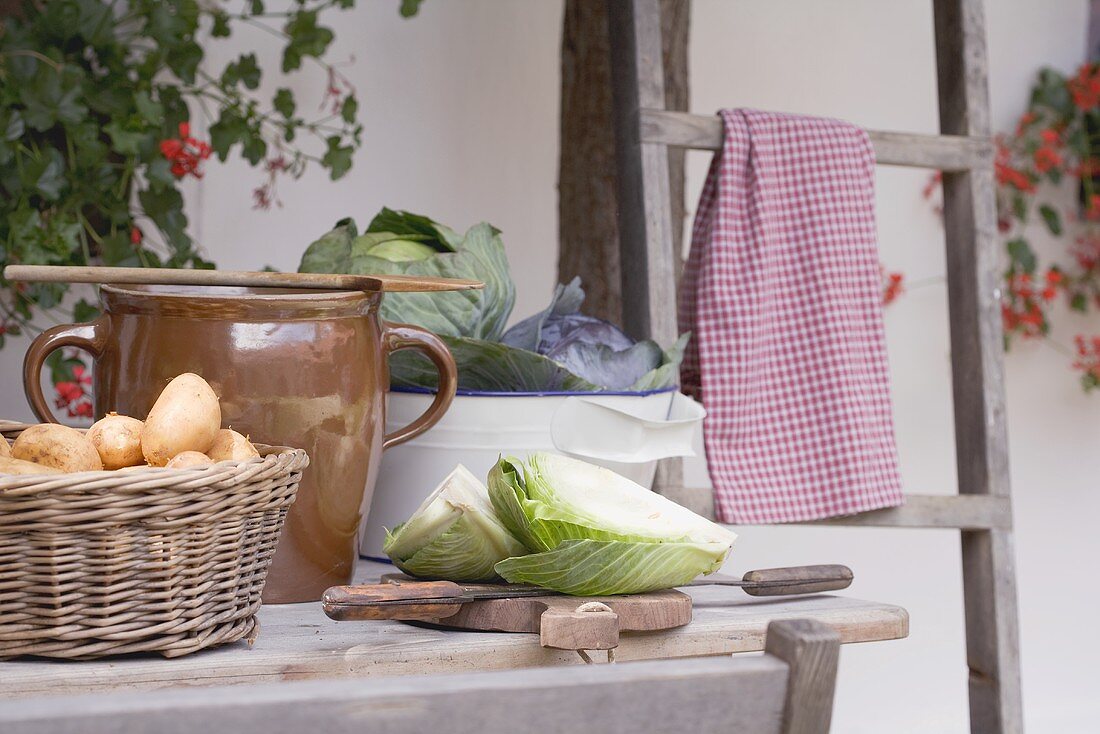 Rustic still life with potatoes & cabbage in front of farmhouse
