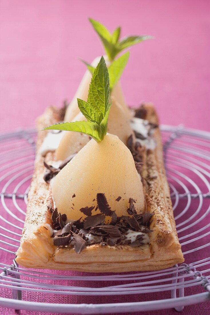 Puff pastry pear tart with grated chocolate on cake rack