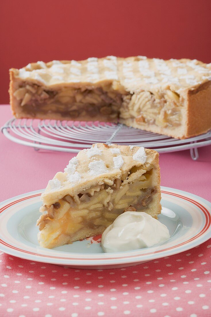 Apple pie with pieces removed, on cake rack, piece on plate