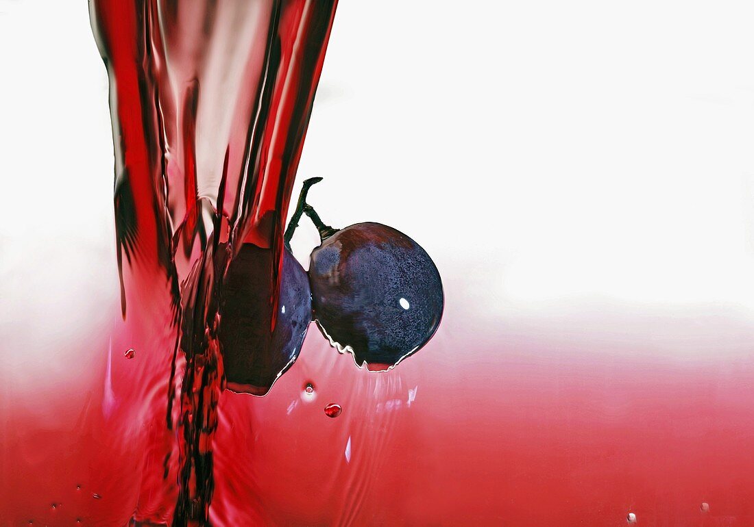 Black grapes in a stream of red wine