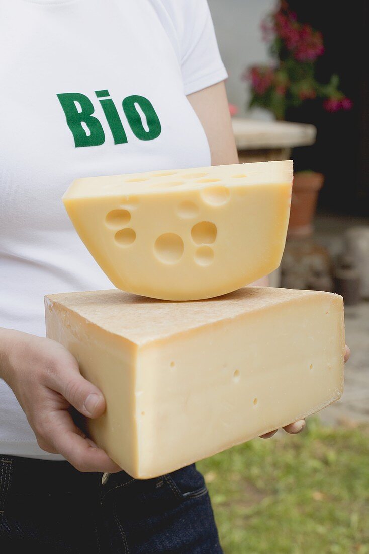 Woman holding two large pieces of organic cheese