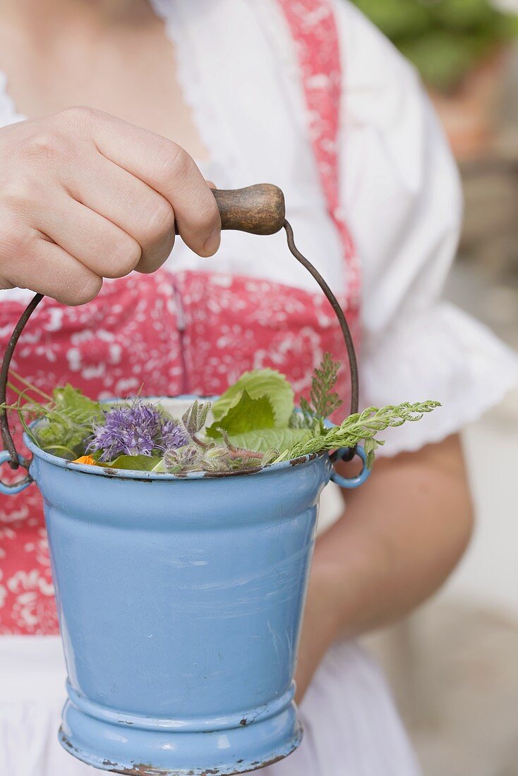 Woman holding fresh herbs in a small bucket