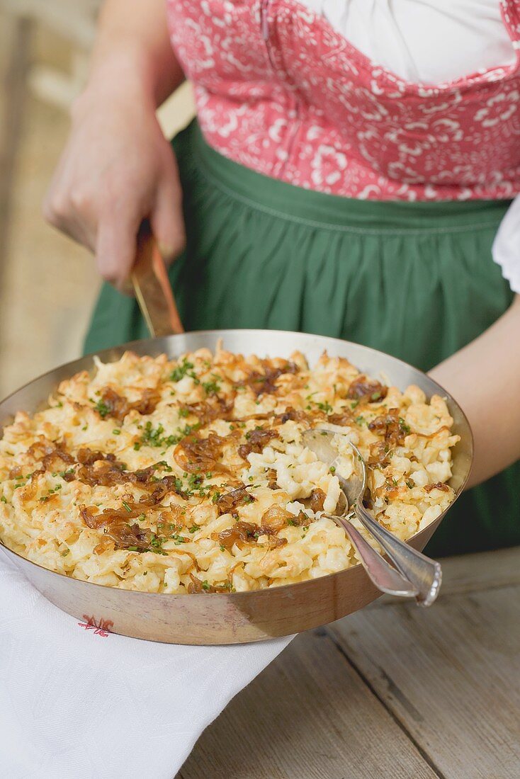 Woman holding a pan of Bauerngröstl (pan-fried potato dish)