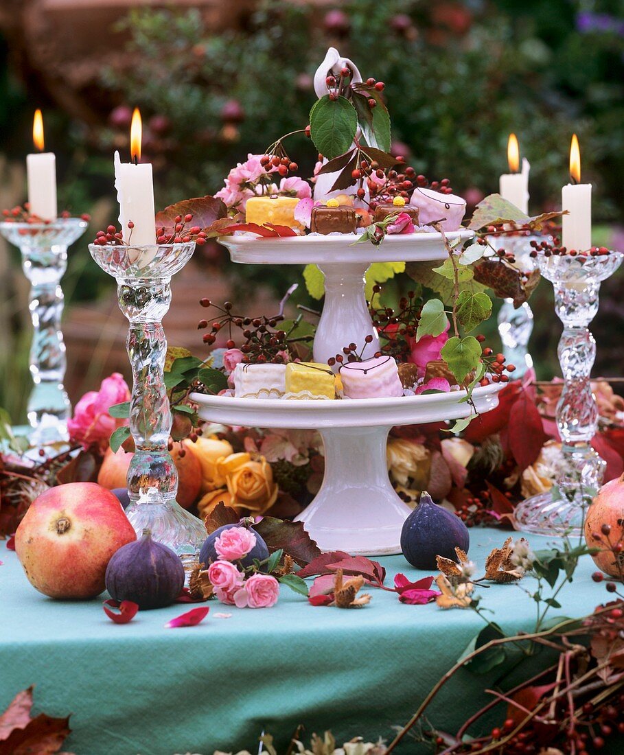 Tiered stand with autumn decorations & petit fours, glass candlestick