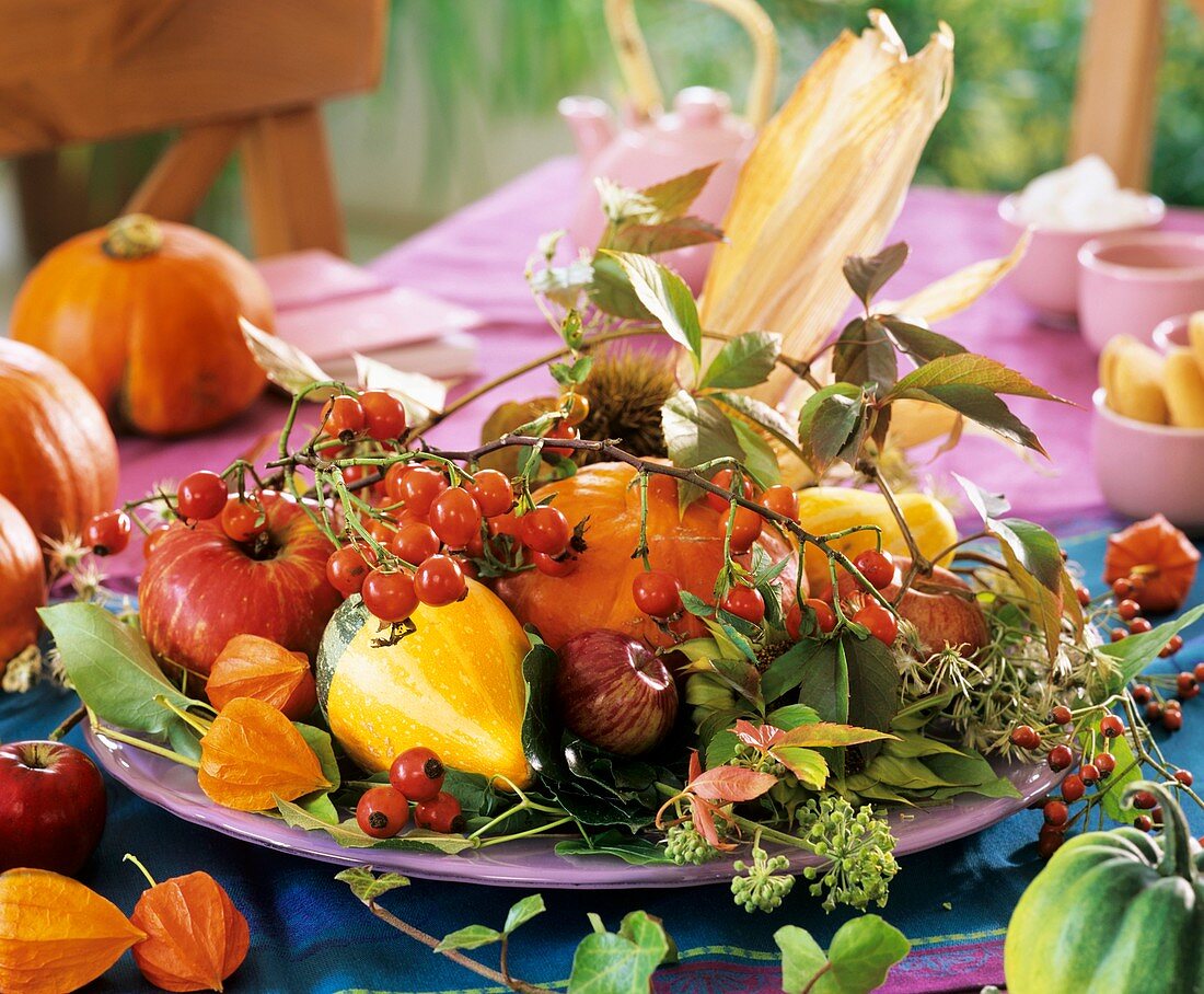 Autumnal plate decoration of rose hips and ornamental gourds