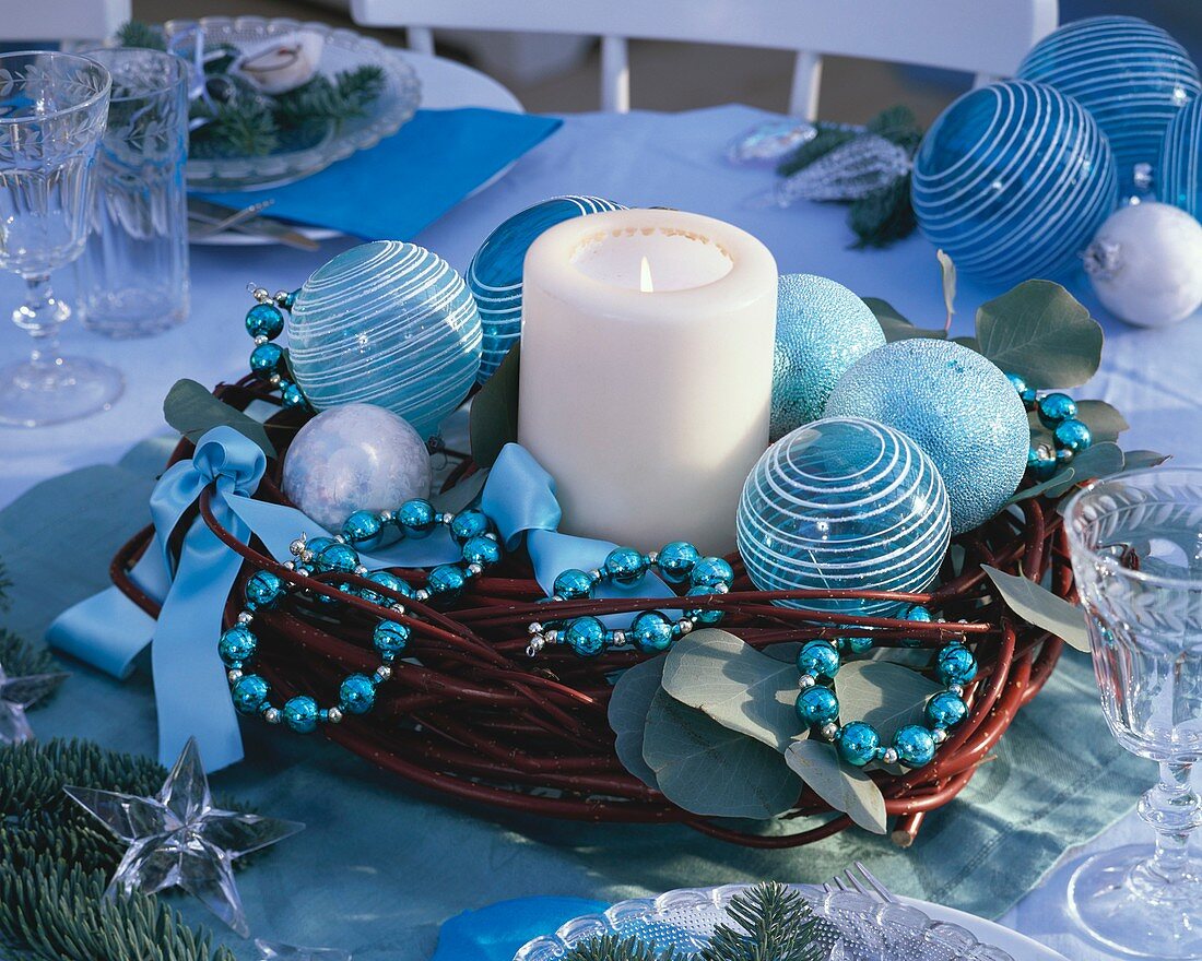 Candle surrounded by dogwood wreath with blue tree ornaments