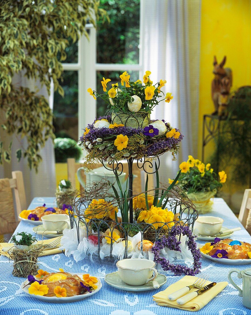 Table laid for Easter with flowers on tiered stand & bread ring