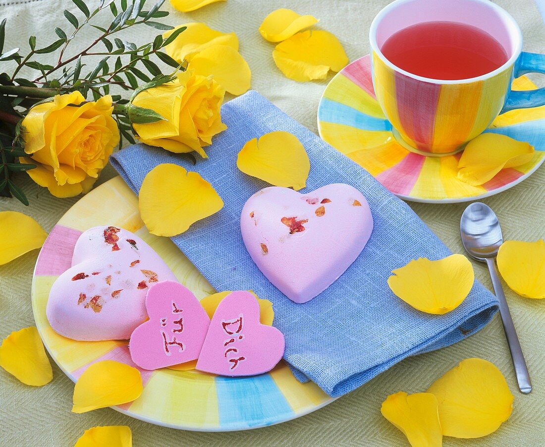 Place-setting with baked hearts, tea and yellow roses