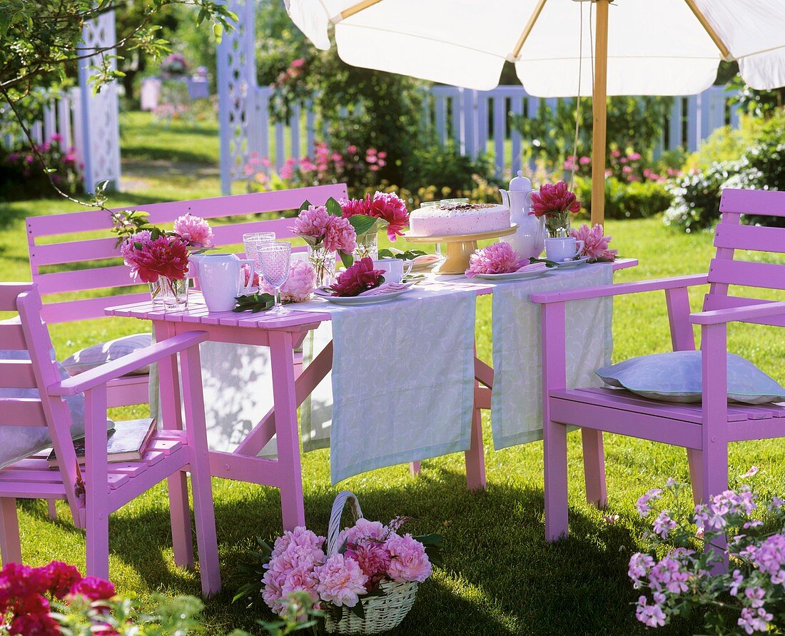 Laid table with peonies and cake in garden