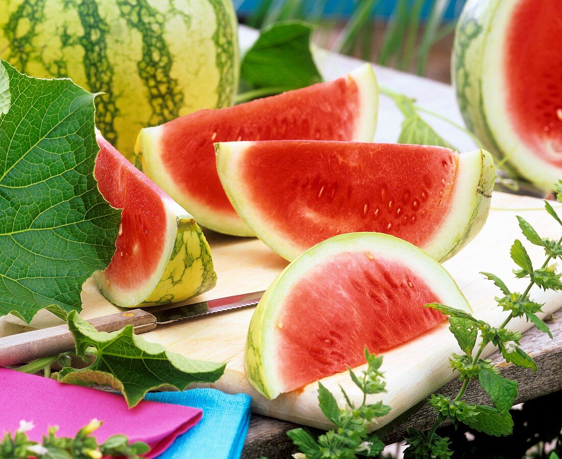 Wassermelone, Schnitze und Blätter auf Schneidbrett