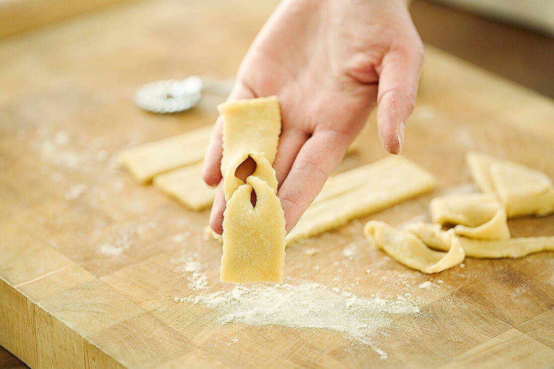 Hand holding uncooked Schürzkuchen (deep-fried pastry)