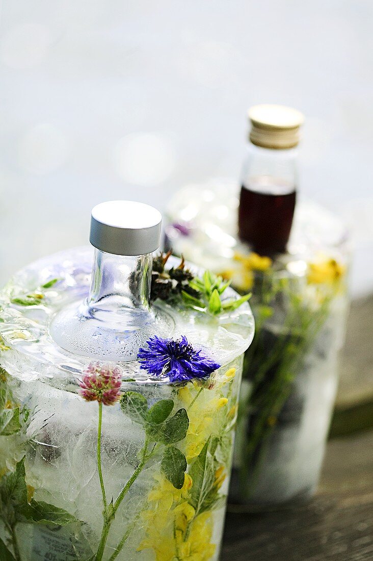Getränke mit Sommerblumen und Eis in Flaschenkühlern